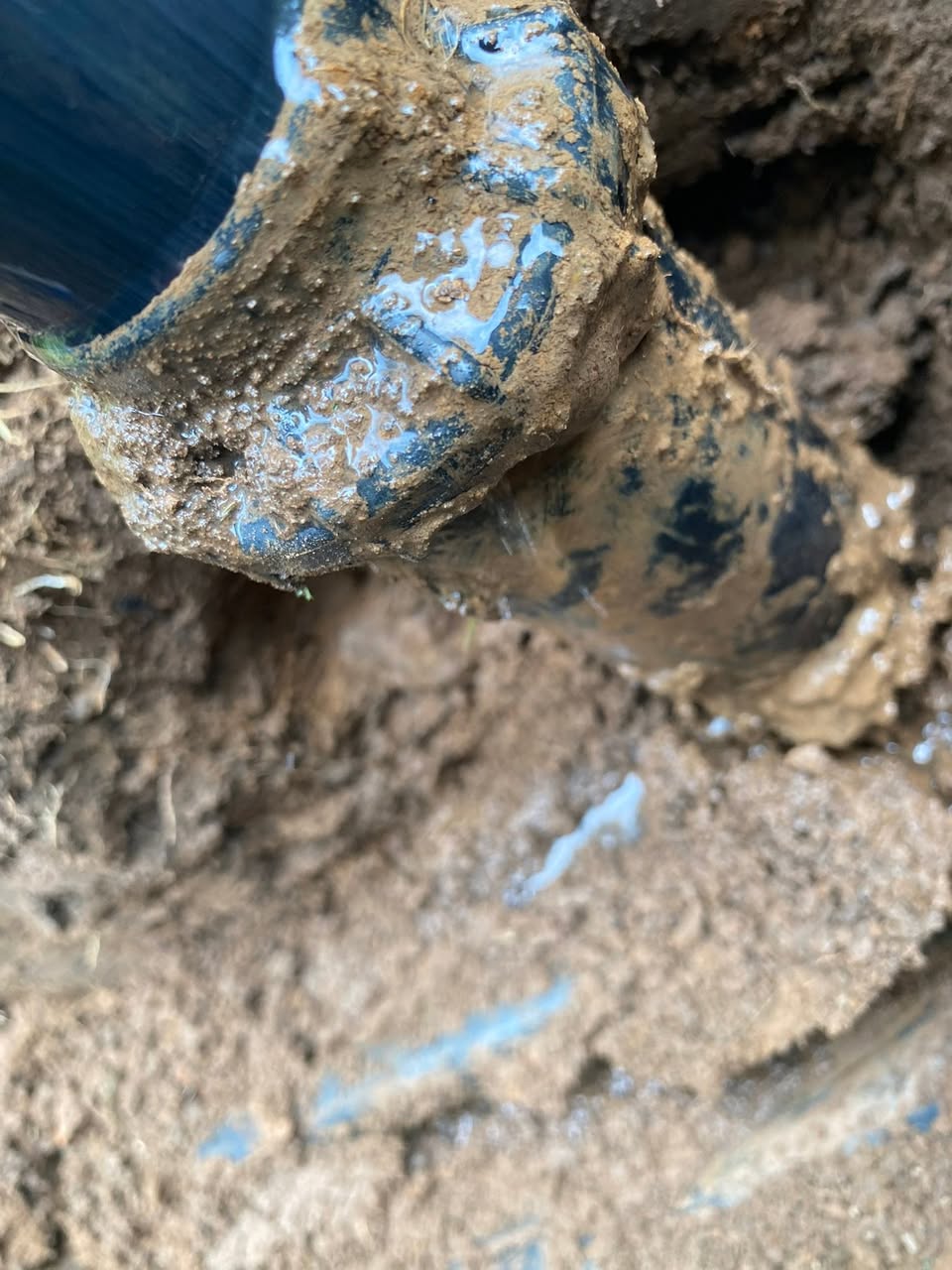 Close-up of an irrigation fitting uncovered in soil.