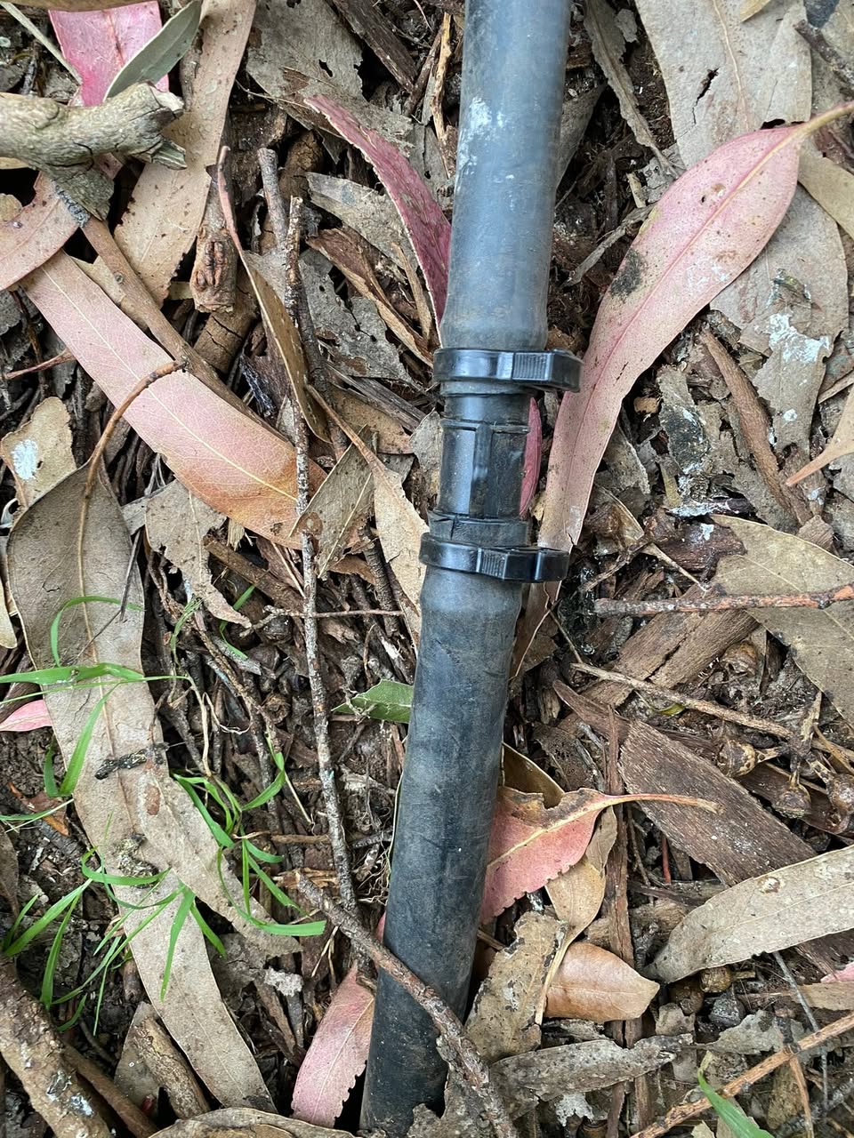 Exposed irrigation pipe in a garden bed during repair.