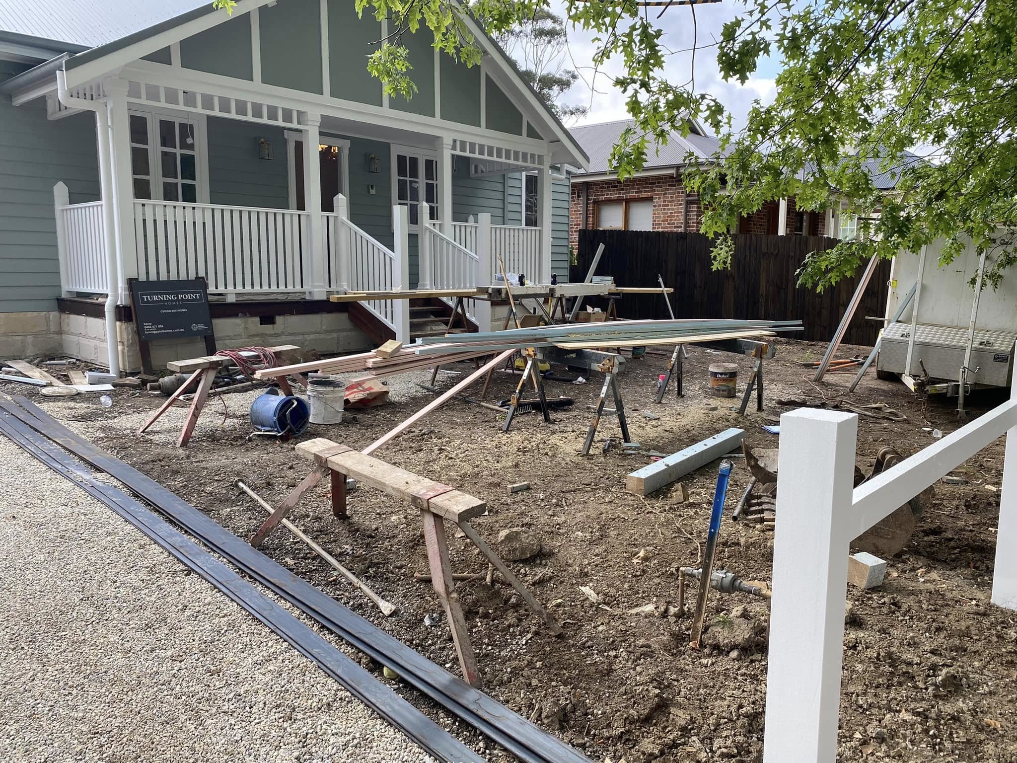 Front yard during construction, with bare soil, edging and fencing work underway.