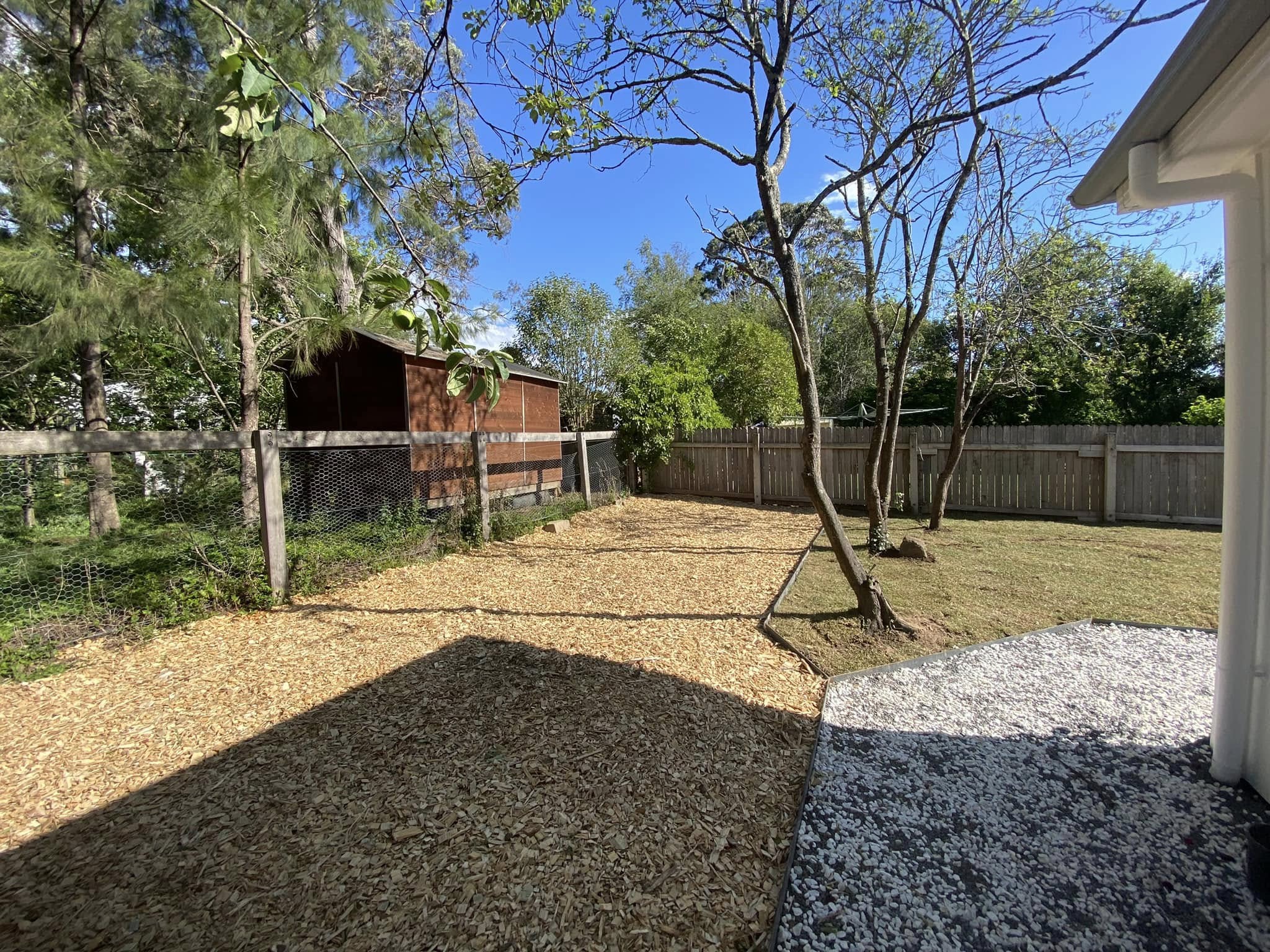 Finished side yard with mulch, lawn, white gravel and timber edging.